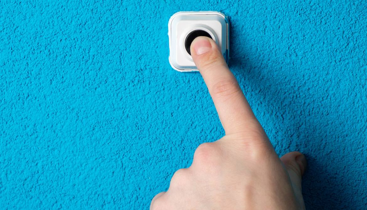 finger pressing doorbell on a blue wall