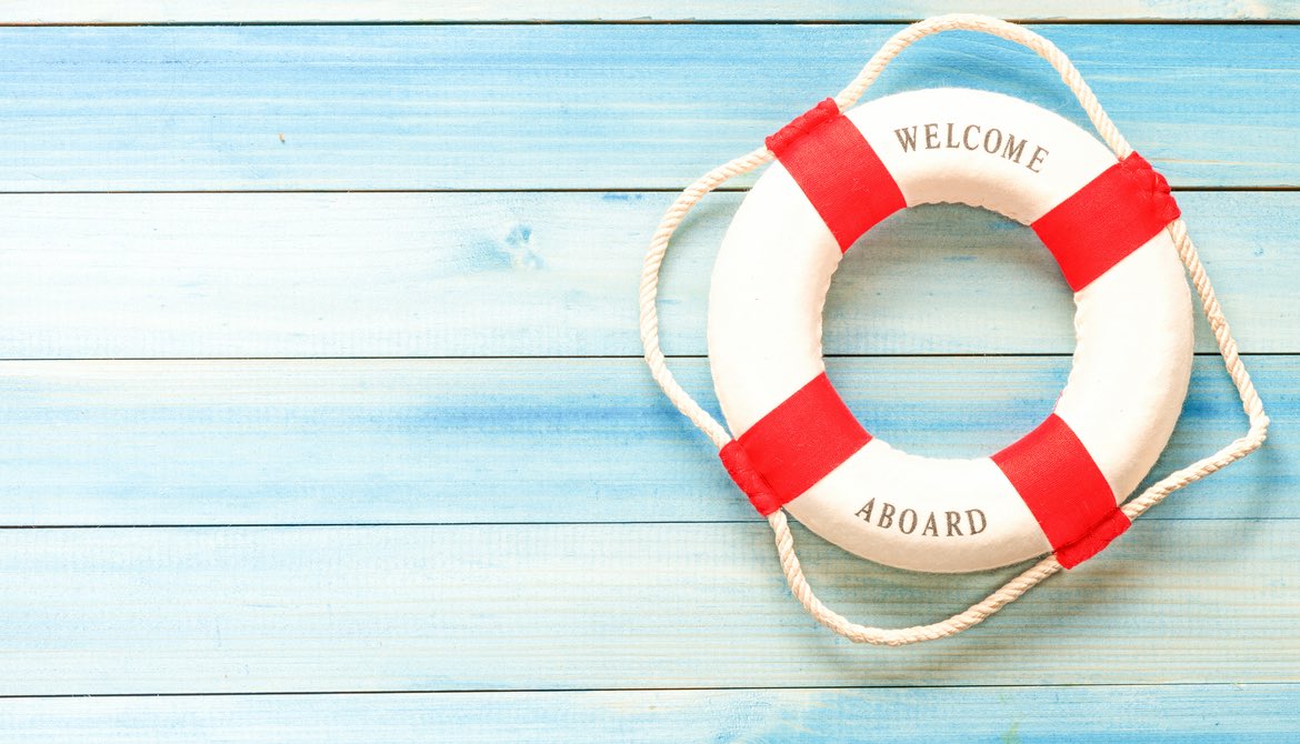 life ring buoy printed with words welcome aboard laying on blue wooden background