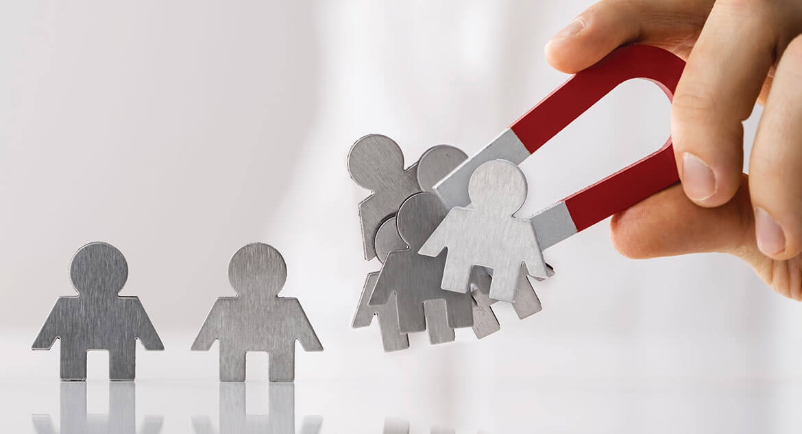 hand holding large horseshoe magnet to attract metal people figures