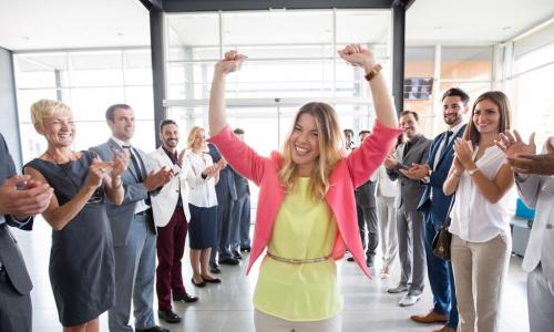 woman walking through a cheering hall of colleagues