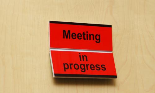 Sign on closed door reads Meeting in Progress