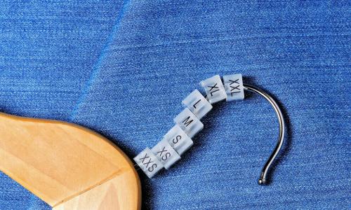 plastic clothing size tags for hangers of clothing store on jeans background