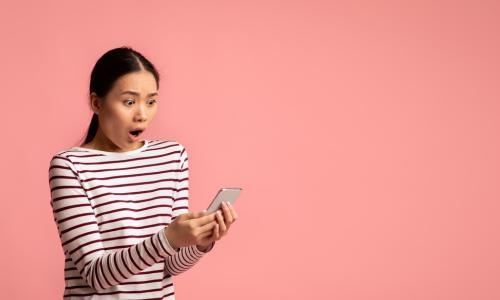 young person looking unhappily surprised while holding phone