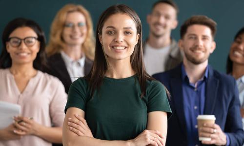 smiling young businesswoman crosses arms and stands in front of group of diverse job candidates 