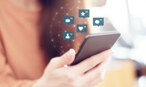 woman’s hand holding smartphone displaying likes comments and engagement icons