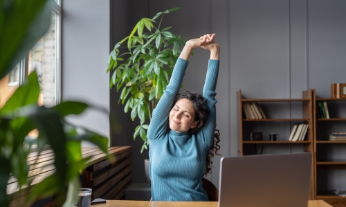 content employee stretching at her desk