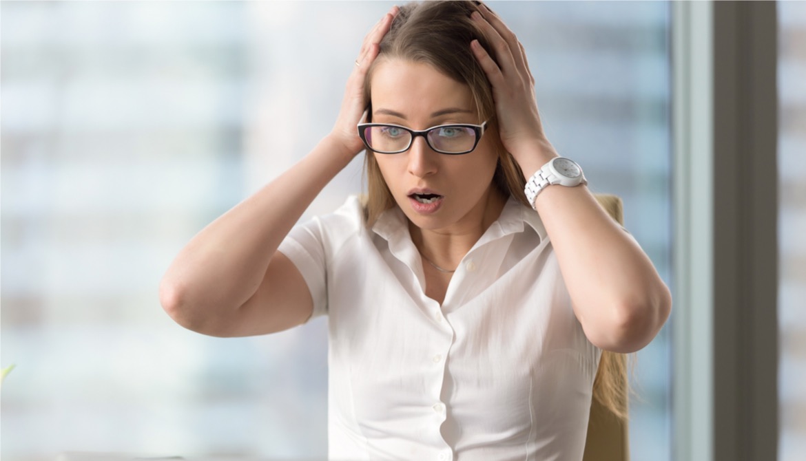 young businesswoman clutching her head and making a horrified face