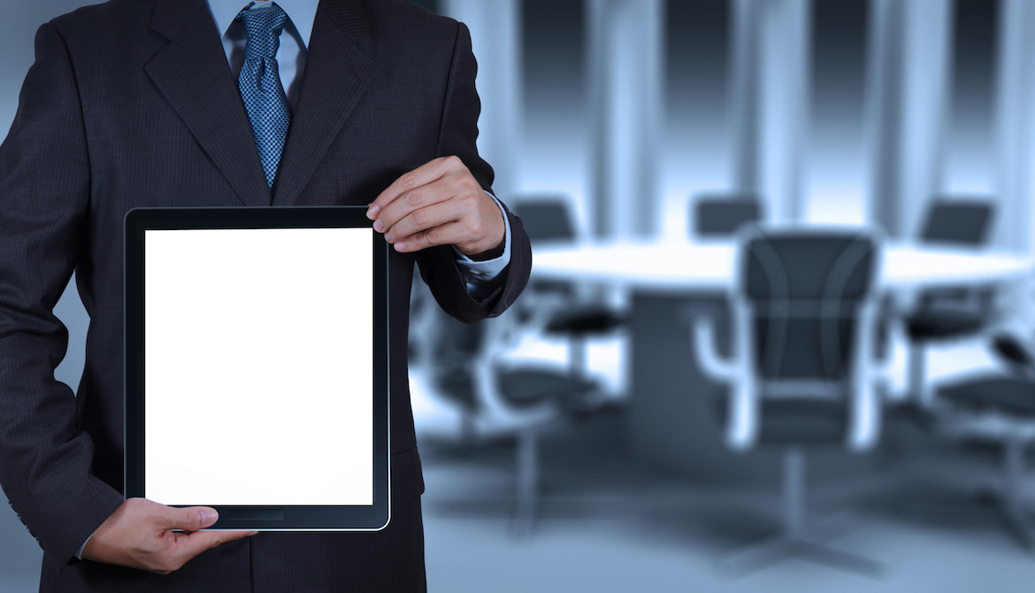 man with tablet standing in front of board table