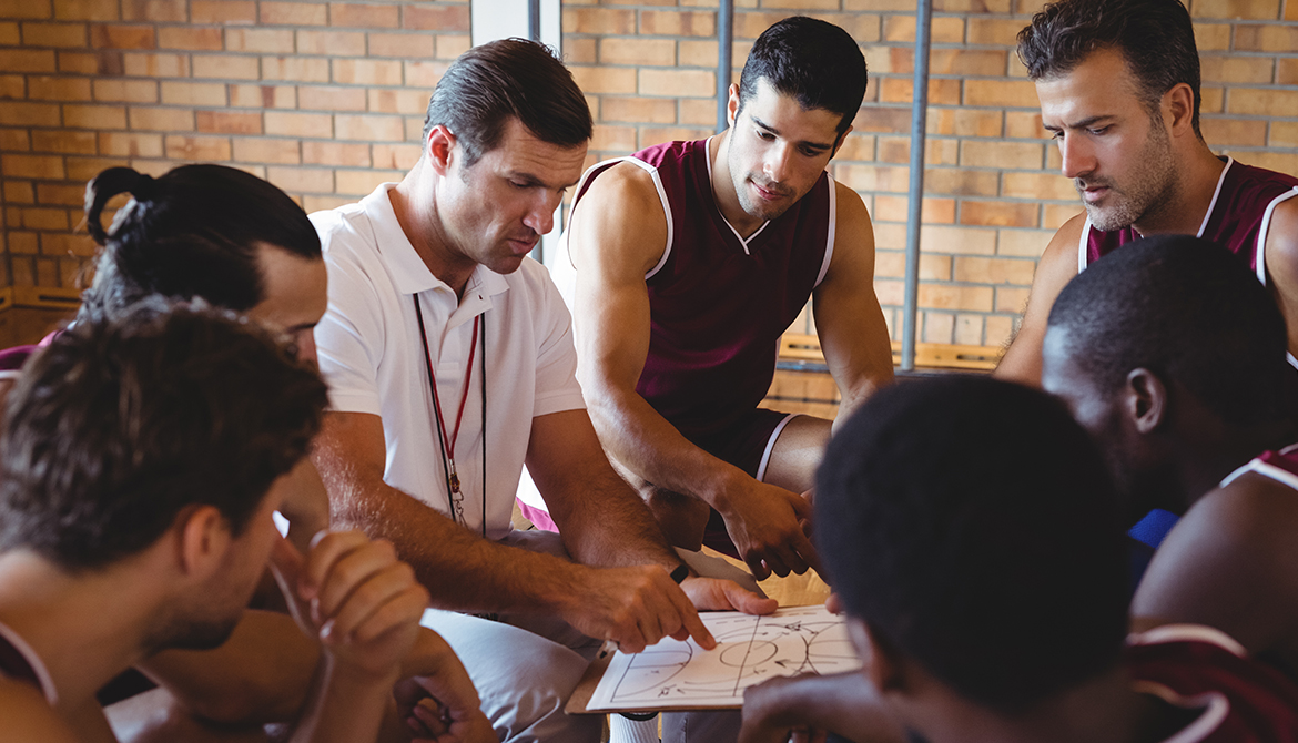 Coach explaining game plan to basketball players in the court