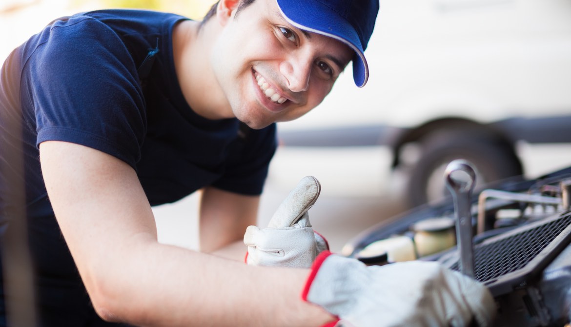 smiling mechanic tunes up a car engine