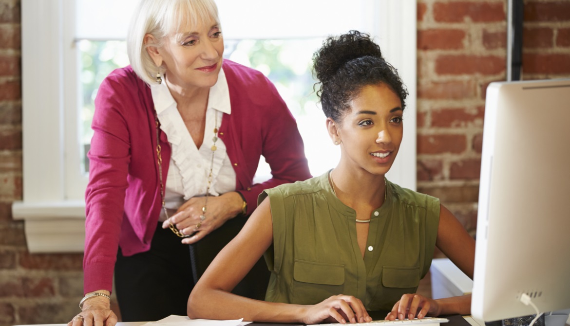 Two Women Working At Computer In Contemporary Office