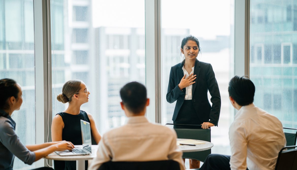 young diverse executive standing up in a meeting to speak