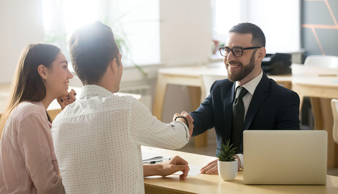 smiling customer service representative shaking hands and greeting a couple