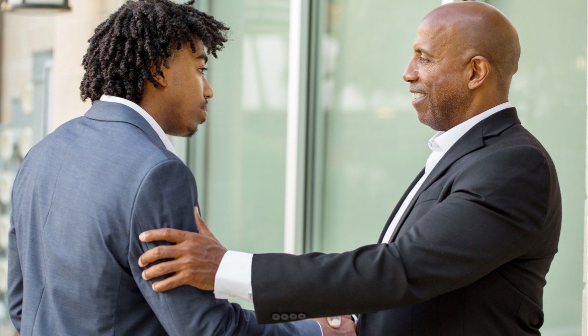 senior executive mentor shaking hands with young trainee