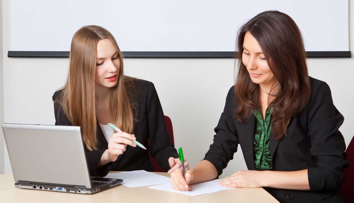 Two business women work with documents