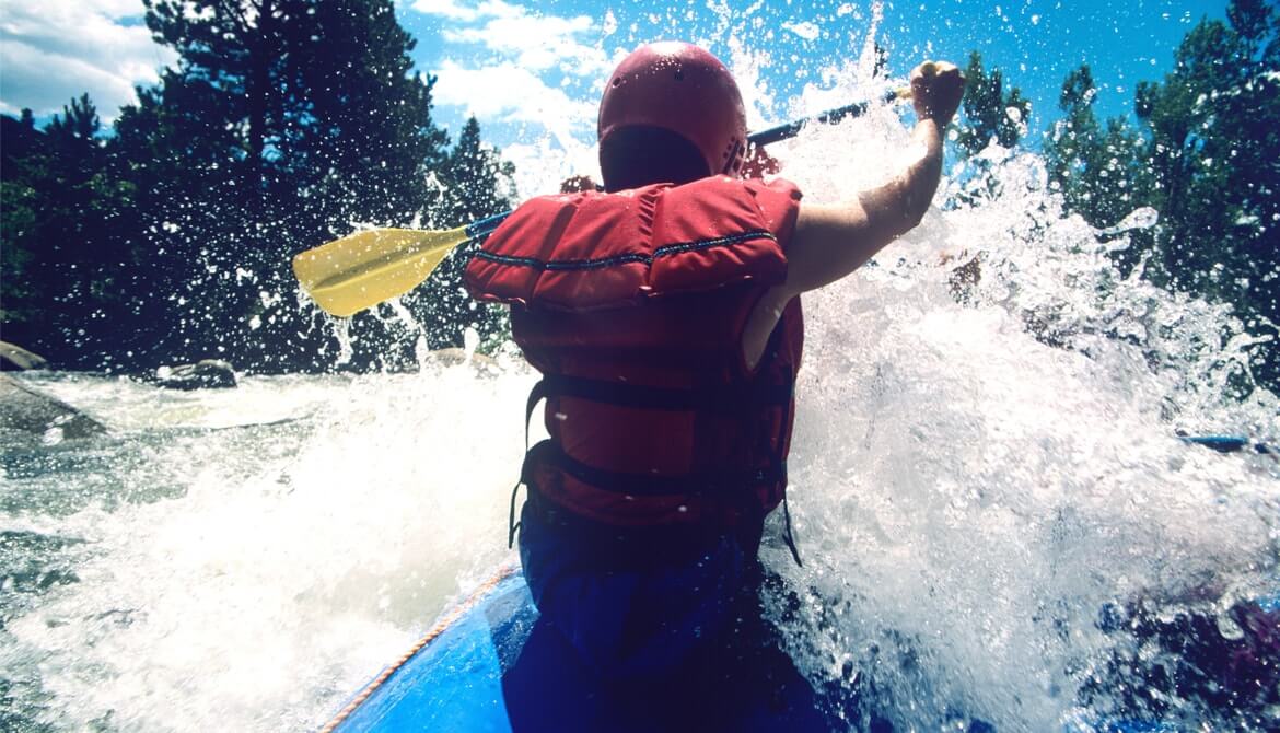 male kayaker paddling through rapids