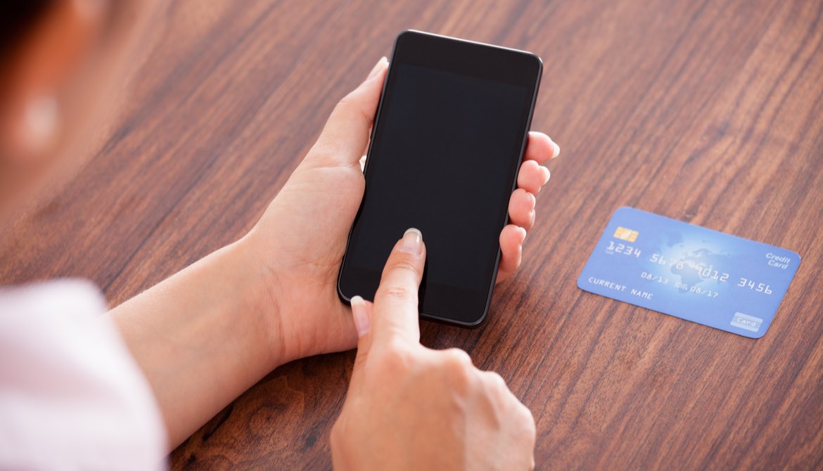 woman using smartphone with credit card to make a payment