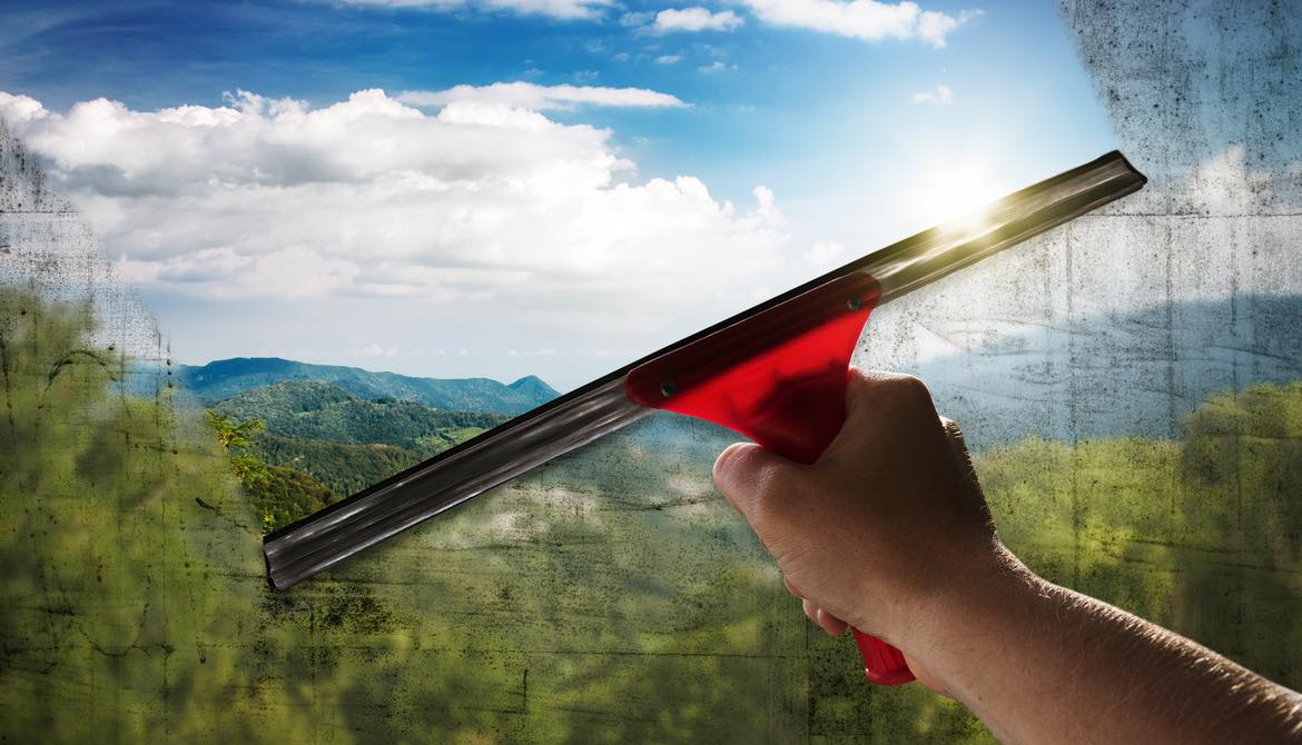 window squeegee washing a window to clear with a beautiful landscape