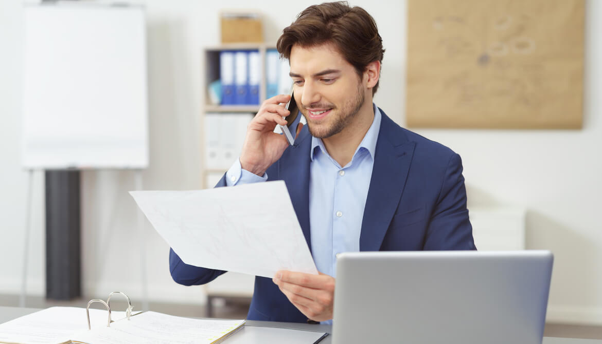 businessman talking on the phone about documents he holds