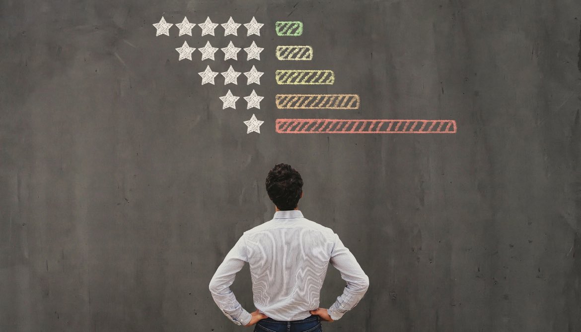 man looking at chalkboard with chart of star ratings