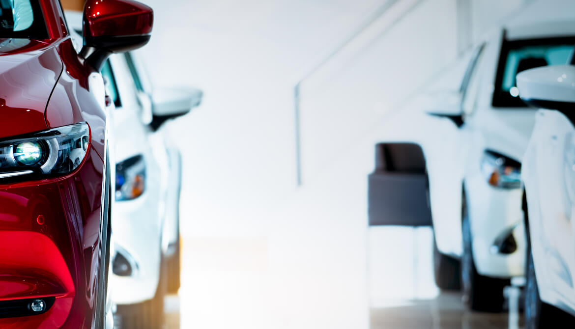 shiny new red and white cars for sale or lease in an empty white dealership showroom