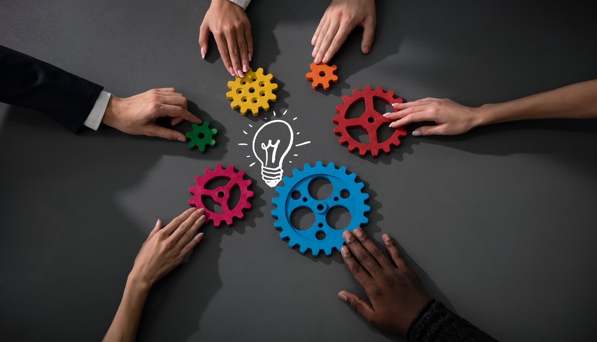 diverse hands gears light bulb on table