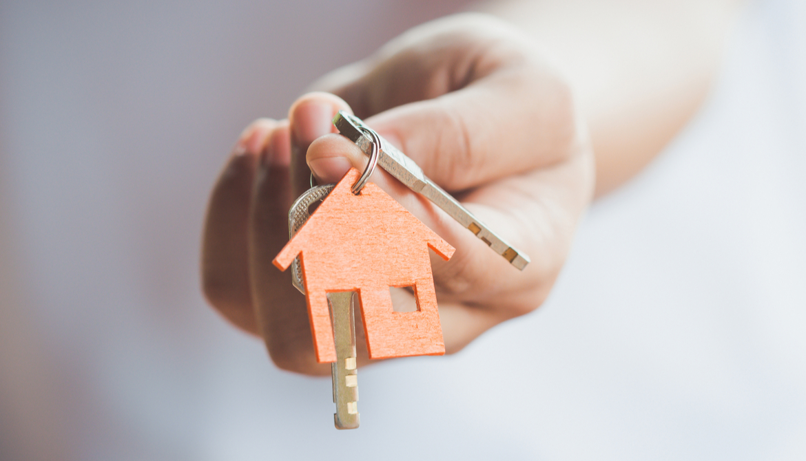 wooden house on key ring held by a hand