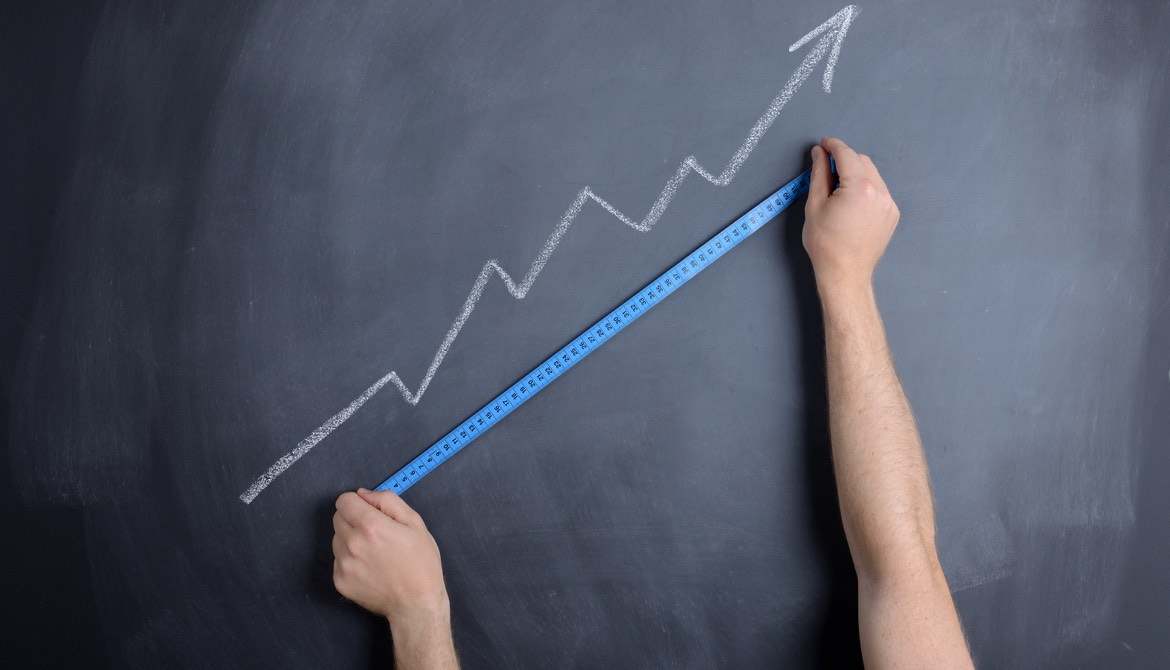 man measures blue arrow on chalkboard