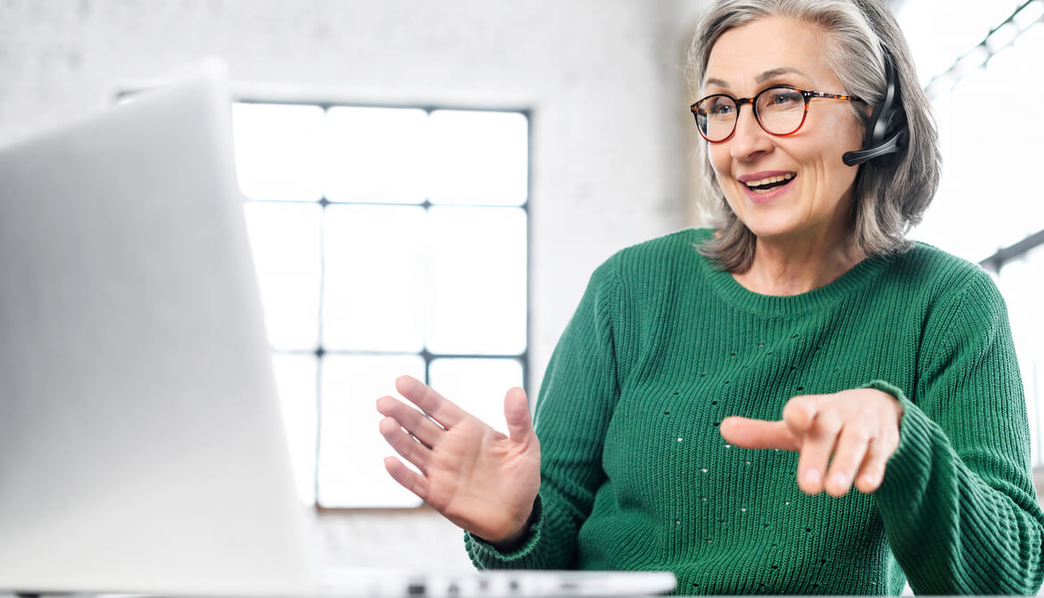 mature woman using laptop and headset