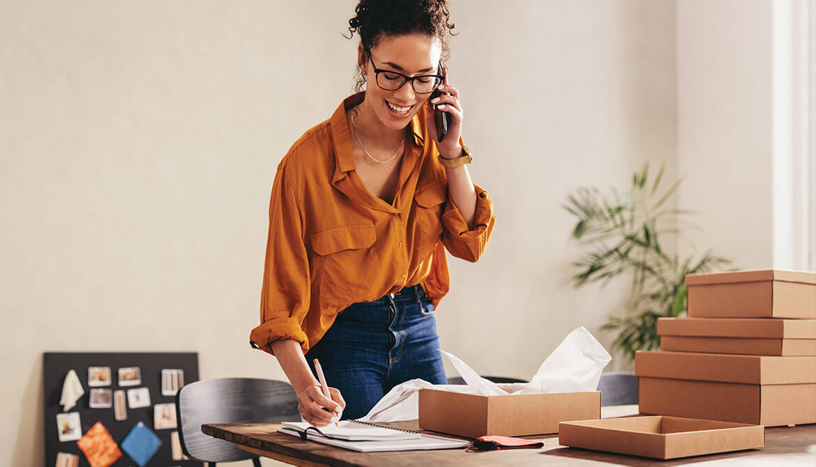 smiling business owner talks on phone in home office