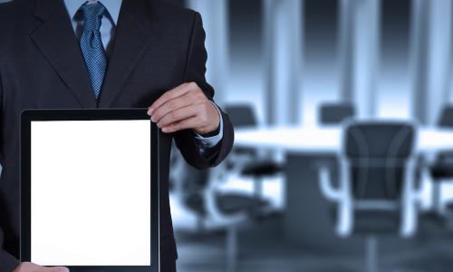 man with tablet standing in front of board table