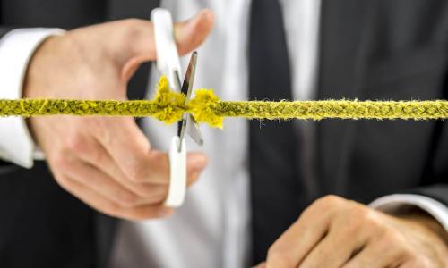 Business man cutting yellow rope