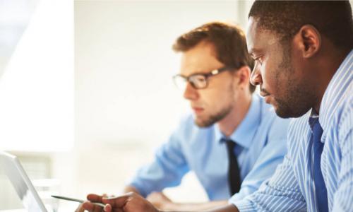 Man pointing at laptop for his colleague