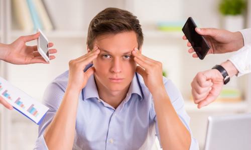 Stressed manager in his office being asked to do too many tasks at once