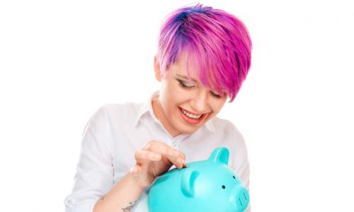 millennial with pink hair putting money in a pig savings bank