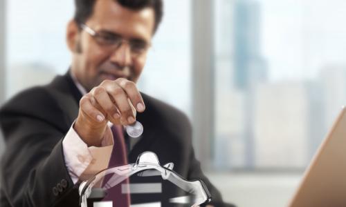 executive depositing coins in a clear piggy bank