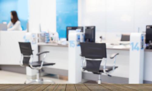 blurred image of a bank credit union lobby over a wooden desk