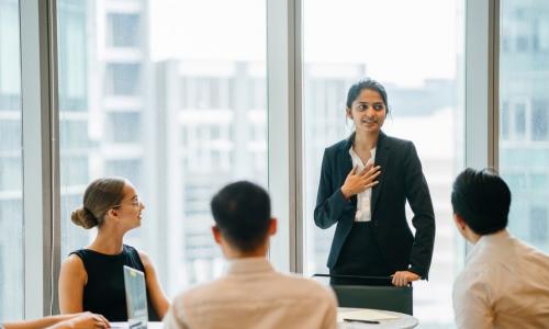 young diverse executive standing up in a meeting to speak