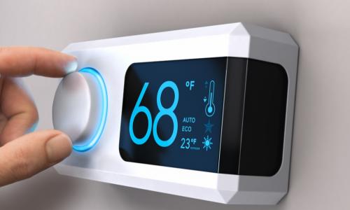 hand adjusting a digital thermostat set to 68 degrees