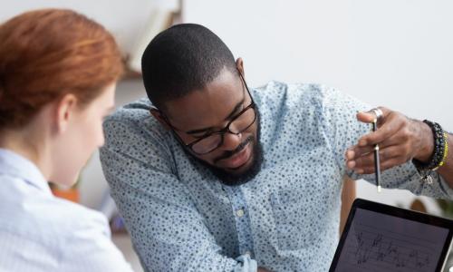 African-American man teaching a red-headed women over a computer