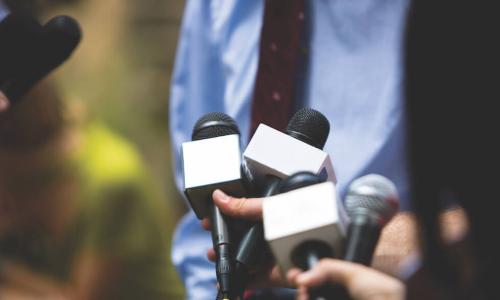 executive at a press conference in front of many microphones 