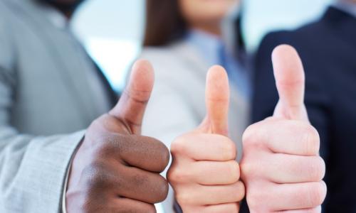 three executives of diverse ethnicities with their thumbs up