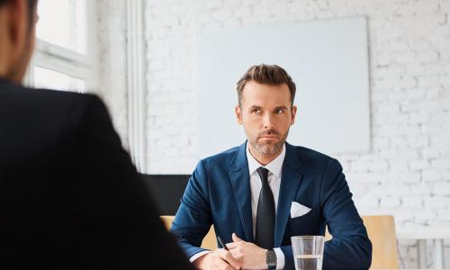 two businessmen sit across from each at a desk