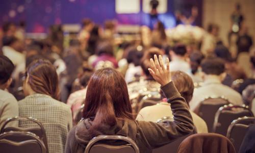 learner with hand up during conference session