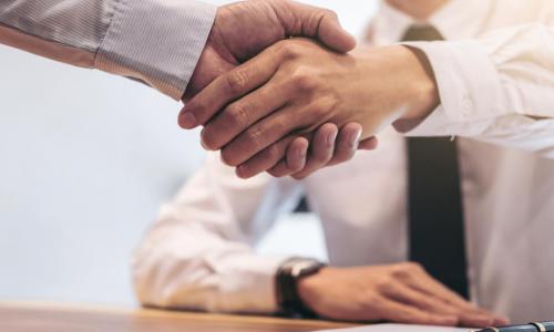 executives shake hands over a contract