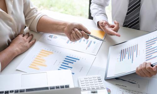 two executives at table with charts and graphs