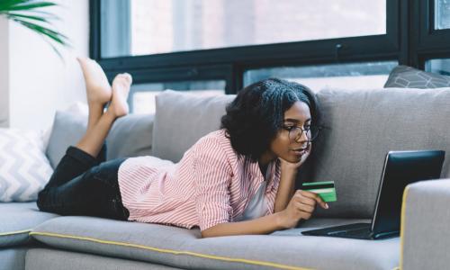 young African American woman using credit card and laptop