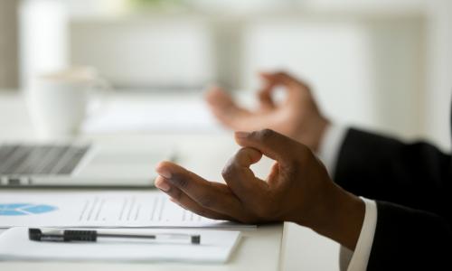 hands of a man meditating at his desk