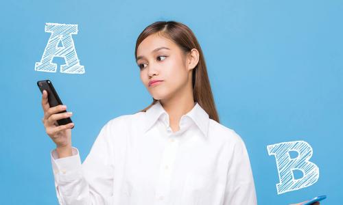 Thoughtful young woman weighing two smartphones labeled A and B