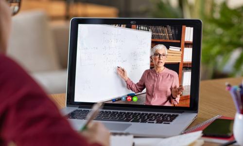 student learning online from teacher shown on laptop screen